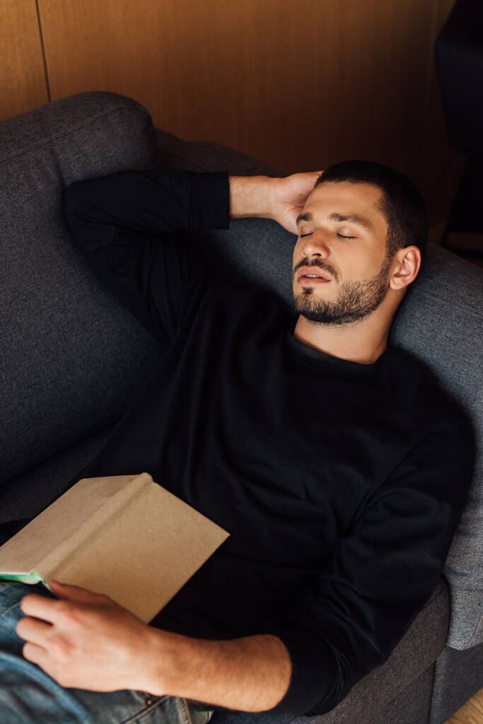 könyv szakállas és jóképű férfi alszik a nappaliban  - Fotó, kép