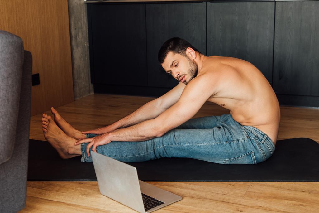 homme torse nu pratiquant sur tapis de yoga et regarder la formation de yoga en ligne sur ordinateur portable
  - Photo, image