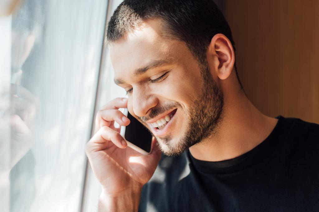 счастливый мужчина разговаривает по смартфону у окна дома
  - Фото, изображение