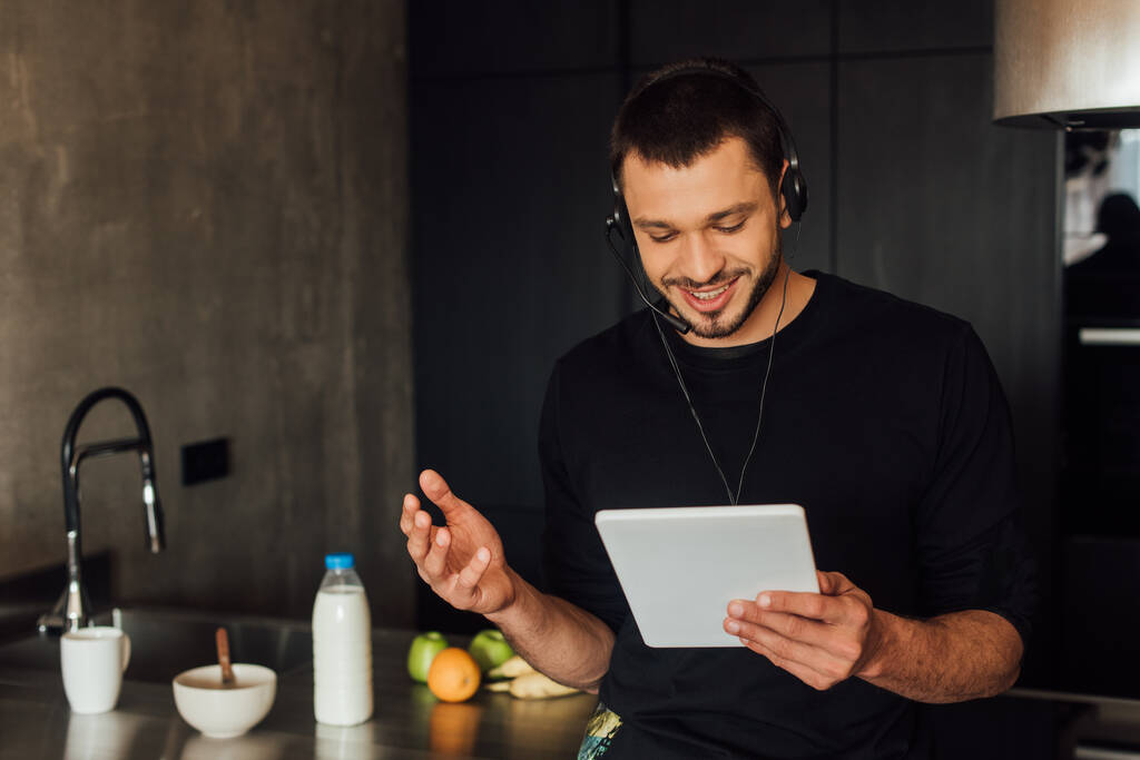 szczęśliwy freelancer w słuchawkach za pomocą tabletu cyfrowego w domu  - Zdjęcie, obraz