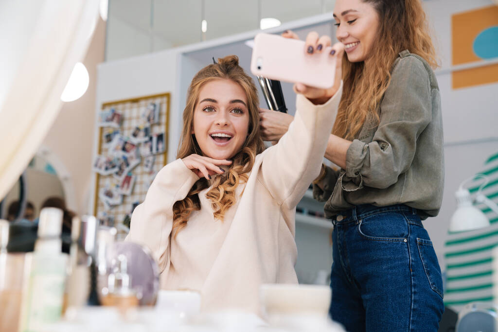 Kuva onnellinen positiivinen nuori kaunis nainen asiakas ottaa selfie hiukset stylisti sedan
. - Valokuva, kuva