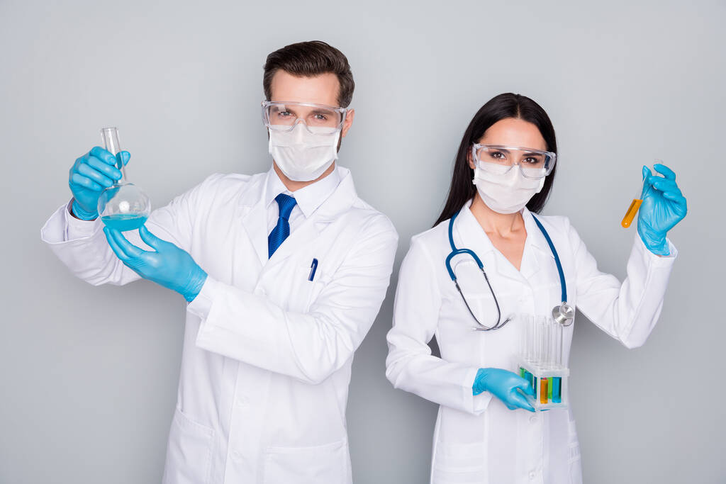 Photo of specialists tapasztalt orvos srác hölgy virológia klinika hold vér szonda fertőzés vakcina vizsgálata kopásvédő maszk kesztyű labor köpeny izolált szürke színű háttér - Fotó, kép