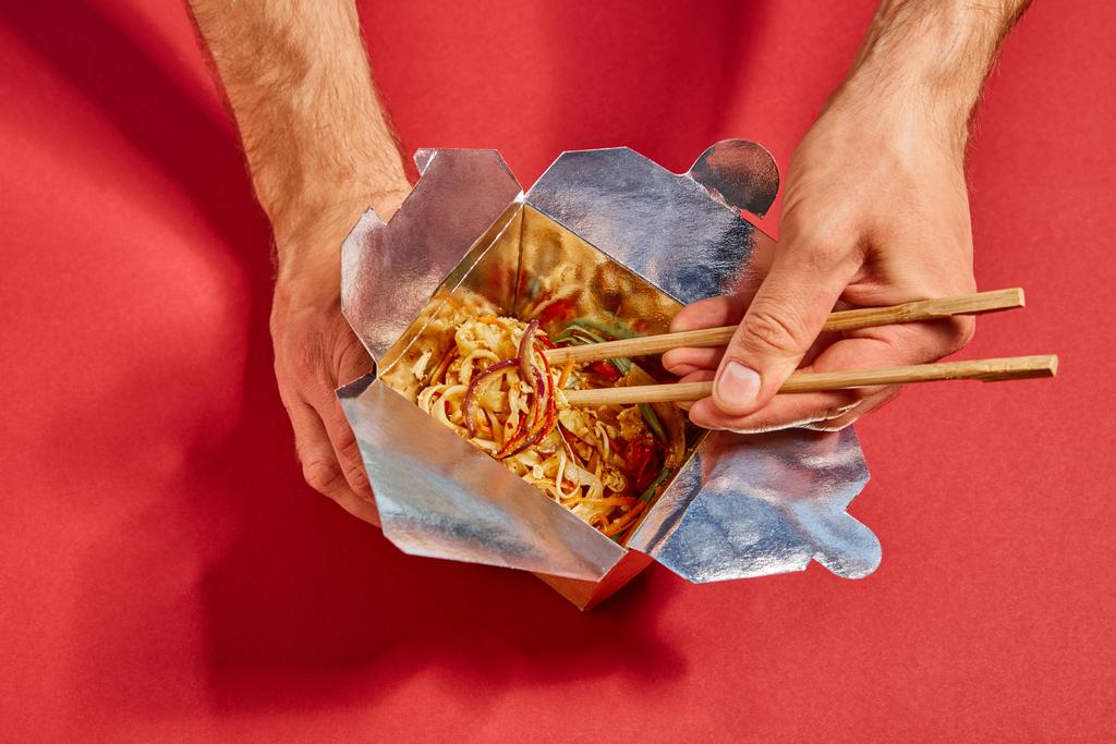 赤いスパイシーな麺のそばに箸を持つ男の上からの眺め - 写真・画像