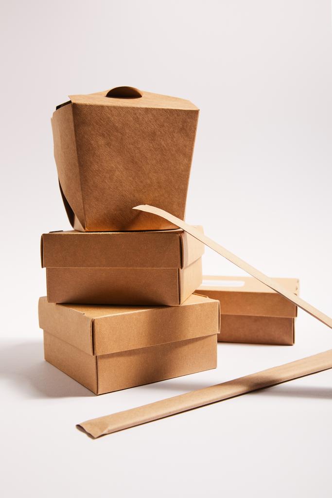 chopsticks em embalagens de papel perto de caixas de papelão takeaway com comida tradicional chinesa em branco
  - Foto, Imagem