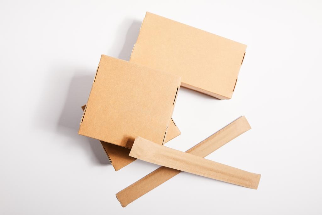 palillos de vista superior en envases de papel cerca de cajas de comida para llevar con comida china en blanco
  - Foto, Imagen