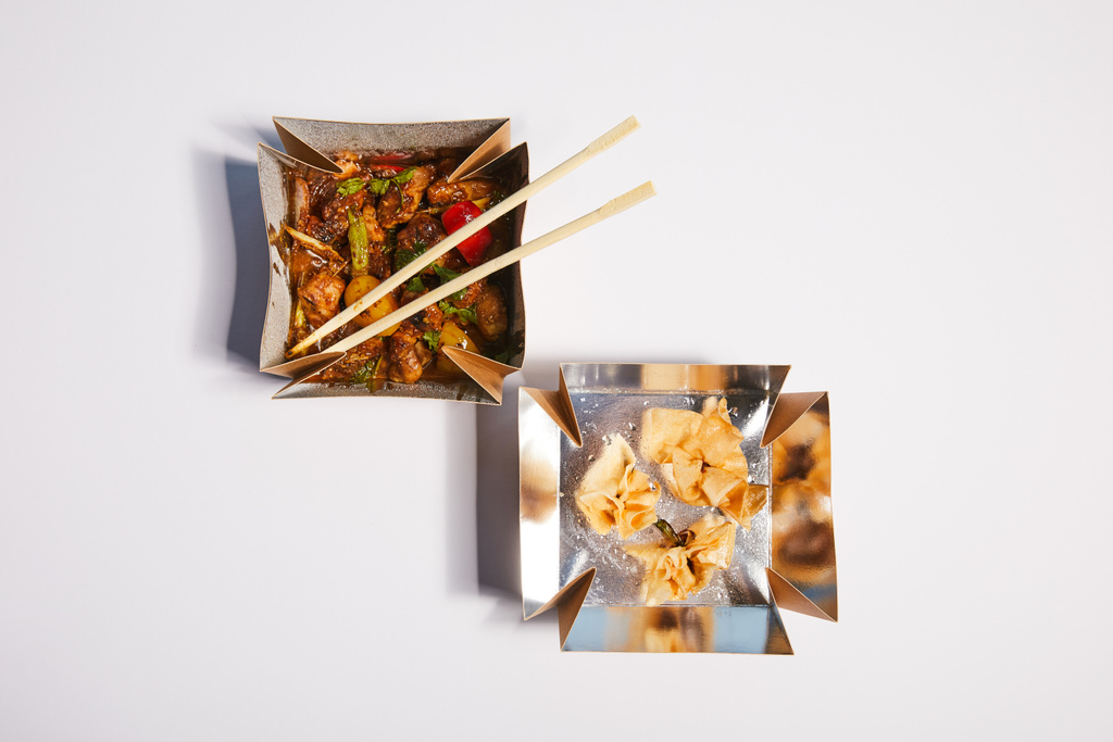 top view of takeaway boxes with fried dumplings and prepared pork with sauce on white  - Photo, Image