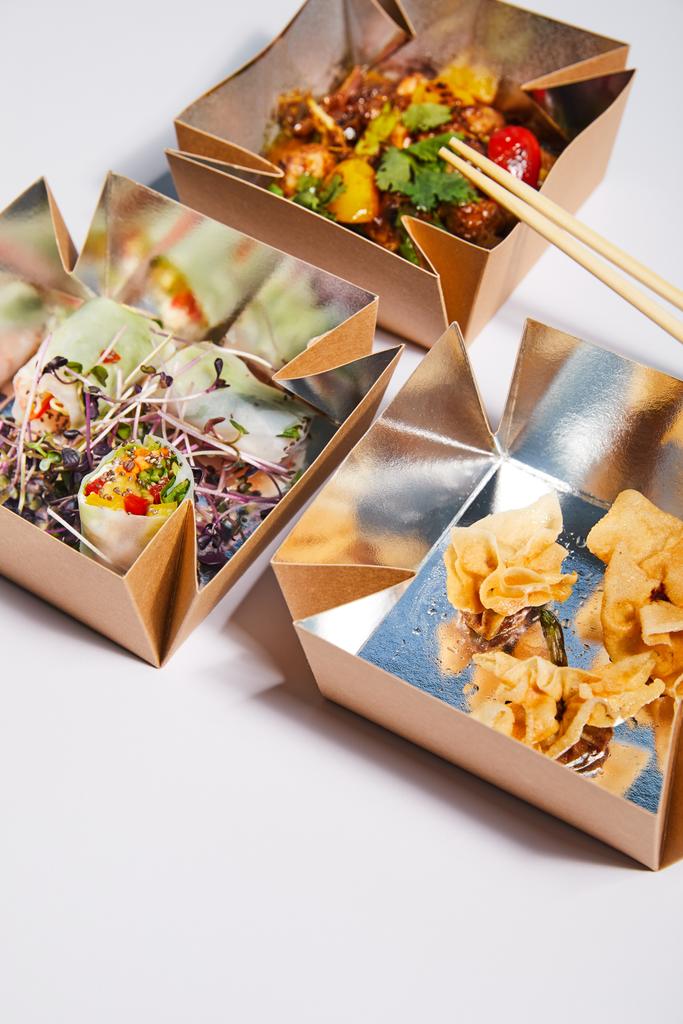 takeaway boxes with tasty and prepared chinese food near chopsticks on white  - Photo, Image
