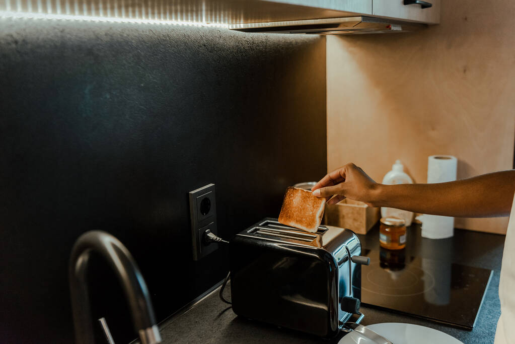 Afro-Amerikalı bir kadının ekmek kızartma makinesinden tost çıkardığı görüntüler. - Fotoğraf, Görsel