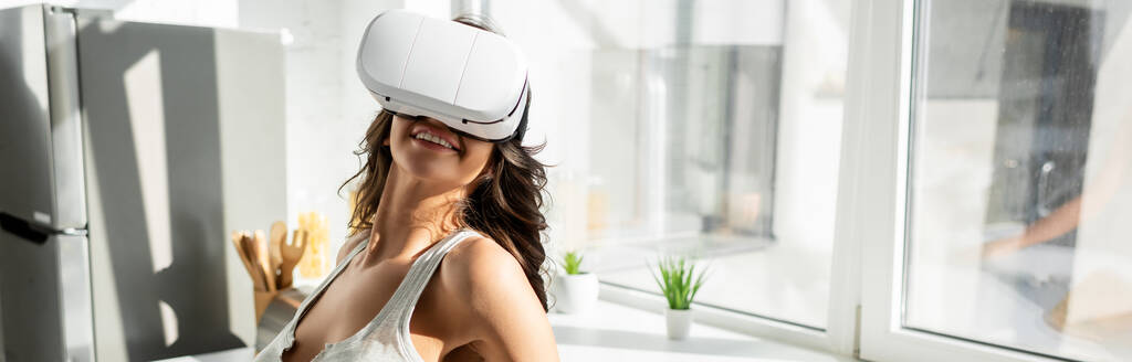 Θετική κοπέλα που χρησιμοποιεί ακουστικά VR στην κουζίνα, πανοραμική λήψη  - Φωτογραφία, εικόνα