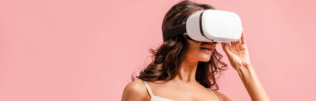 Panoramatická orientace ženy ve sluchátkách virtuální reality izolovaných na růžové - Fotografie, Obrázek