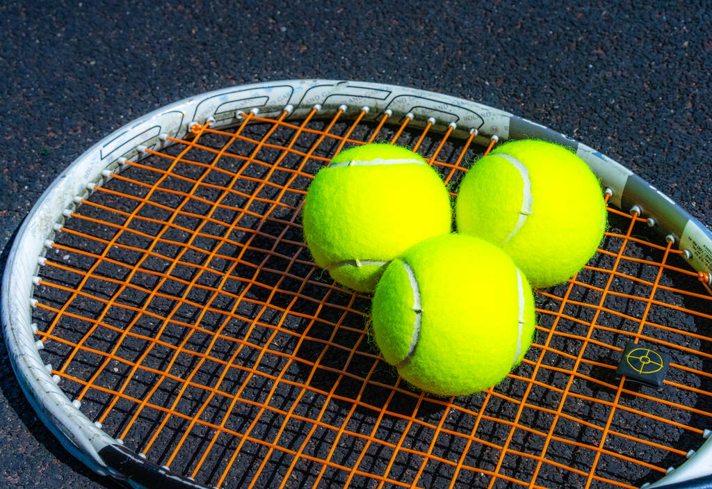テニスボールはテニスラケットの上に横たわる - 写真・画像