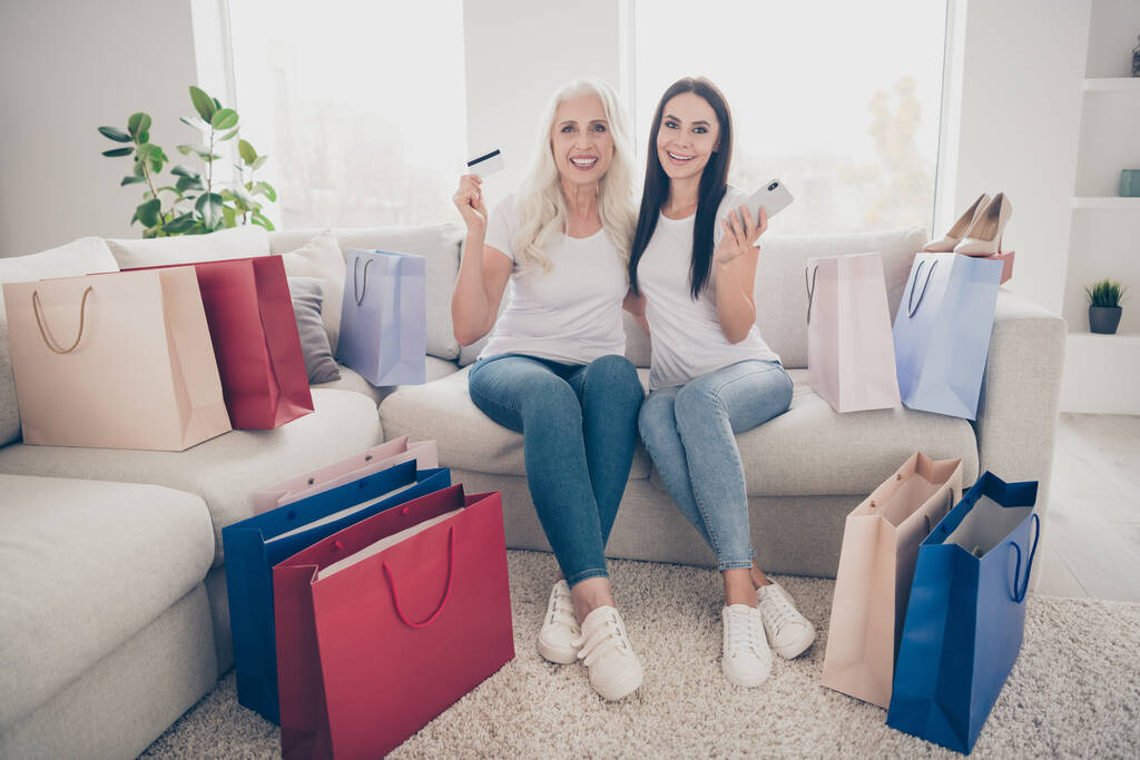 Πορτρέτο των δύο ωραία ελκυστική όμορφη χαρούμενη χαρούμενες γυναίκες παραγγελία νέα ρούχα πράγματα τάση web app παράδοση κάθεται στο ντιβάνι στο λευκό φως εσωτερικό δωμάτιο επίπεδη διαμέρισμα - Φωτογραφία, εικόνα