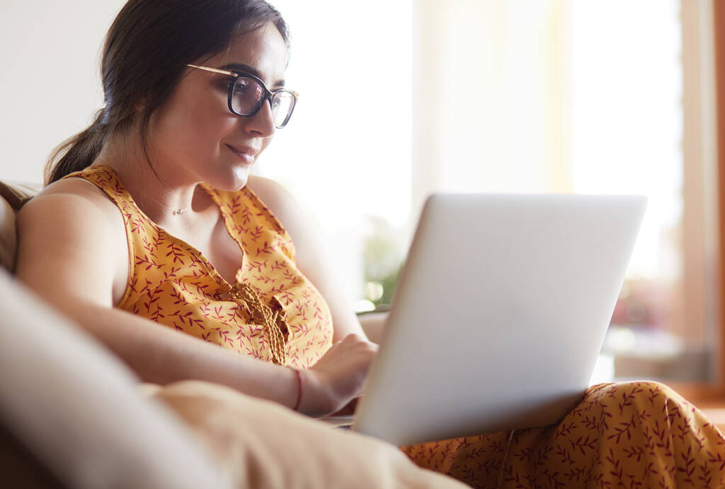 Fiatal nő ül a kanapén dolgozó laptop számítógép otthon - Fotó, kép