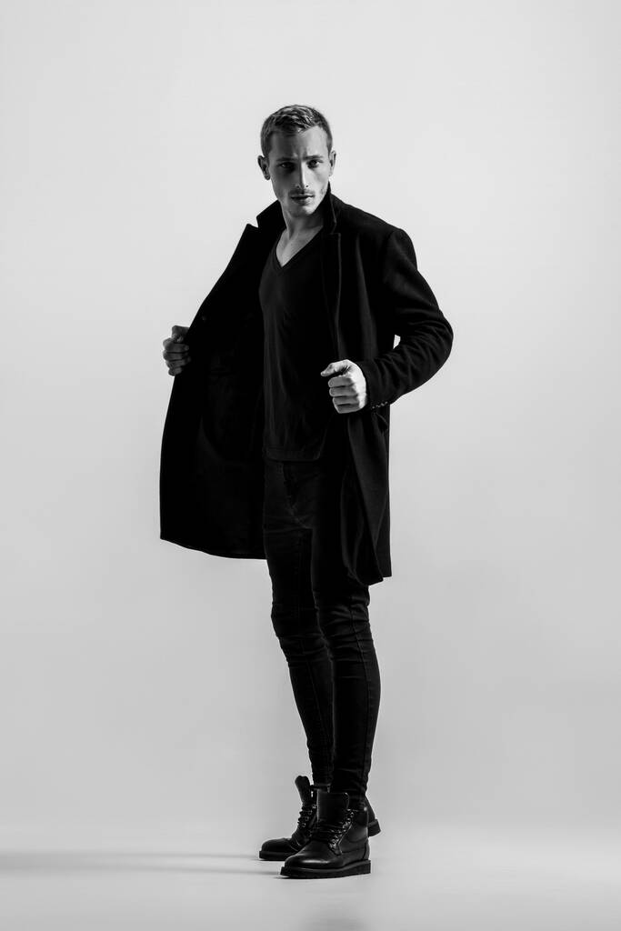 Hombre de moda guapo con abrigo negro posando sobre fondo blanco. Modelo de prueba
 - Foto, imagen