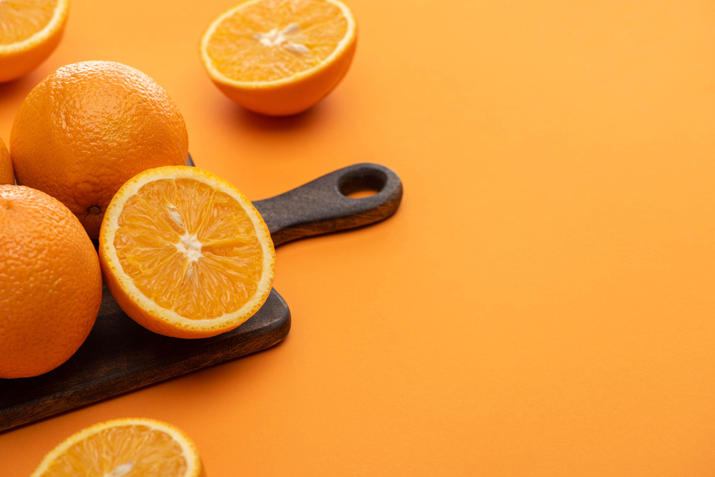 ripe delicious cut and whole oranges on wooden cutting board on colorful background - Photo, Image