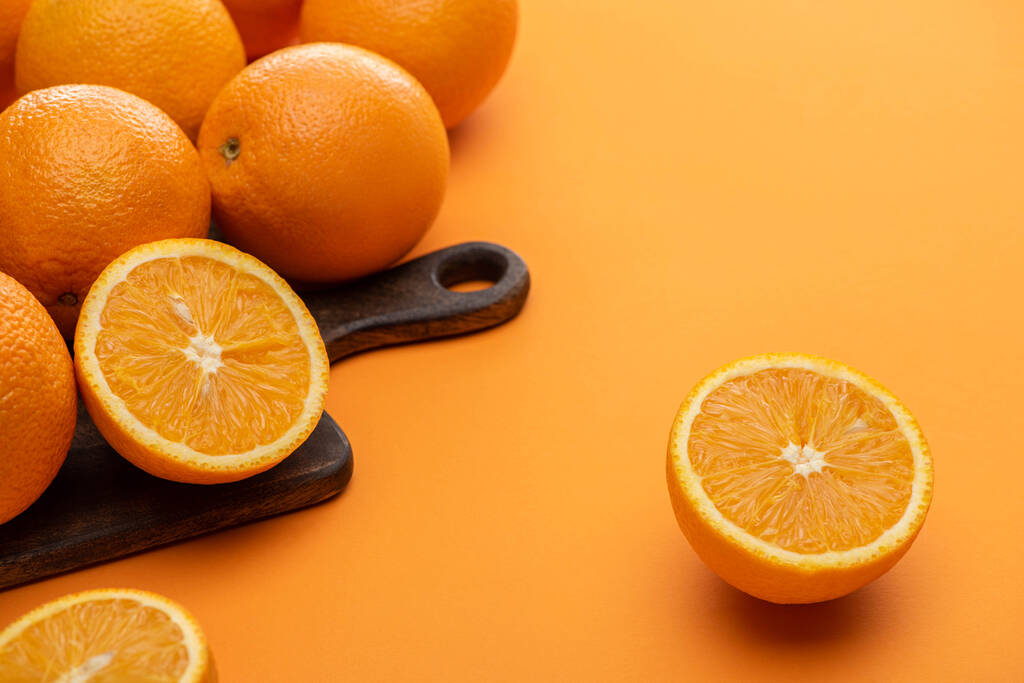 maduro delicioso corte y naranjas enteras en tabla de cortar de madera sobre fondo colorido
 - Foto, imagen
