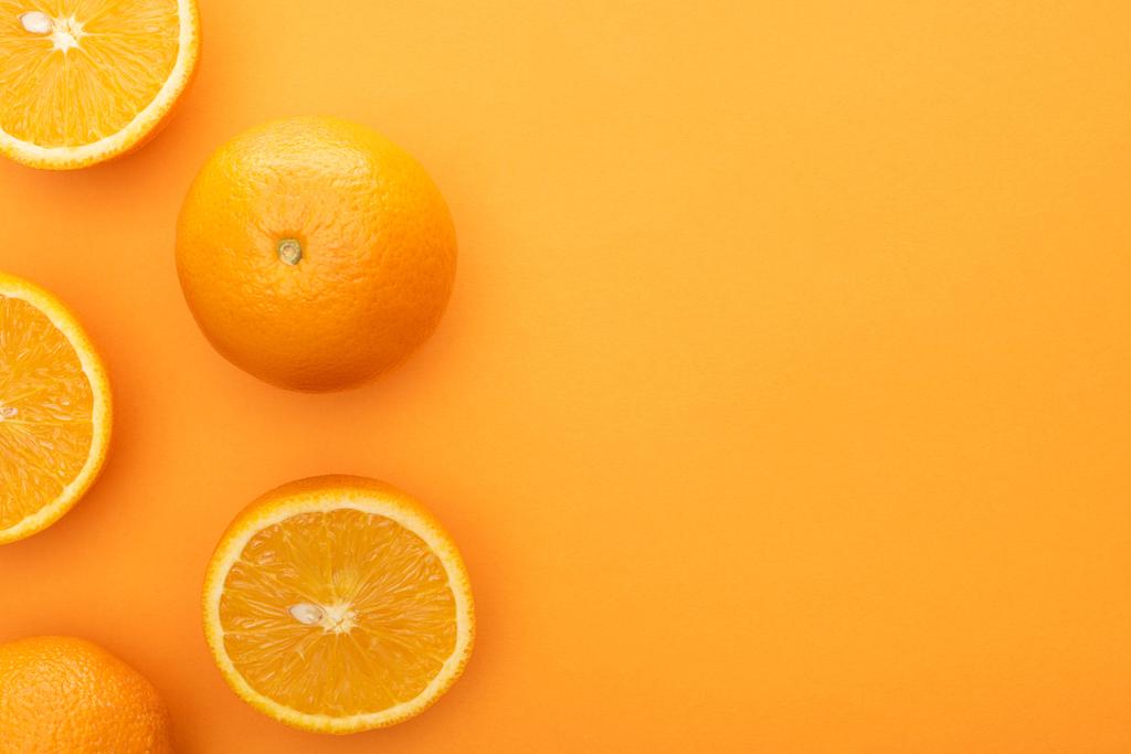 pohled shora na šťavnaté celé pomeranče a plátky na barevném pozadí - Fotografie, Obrázek