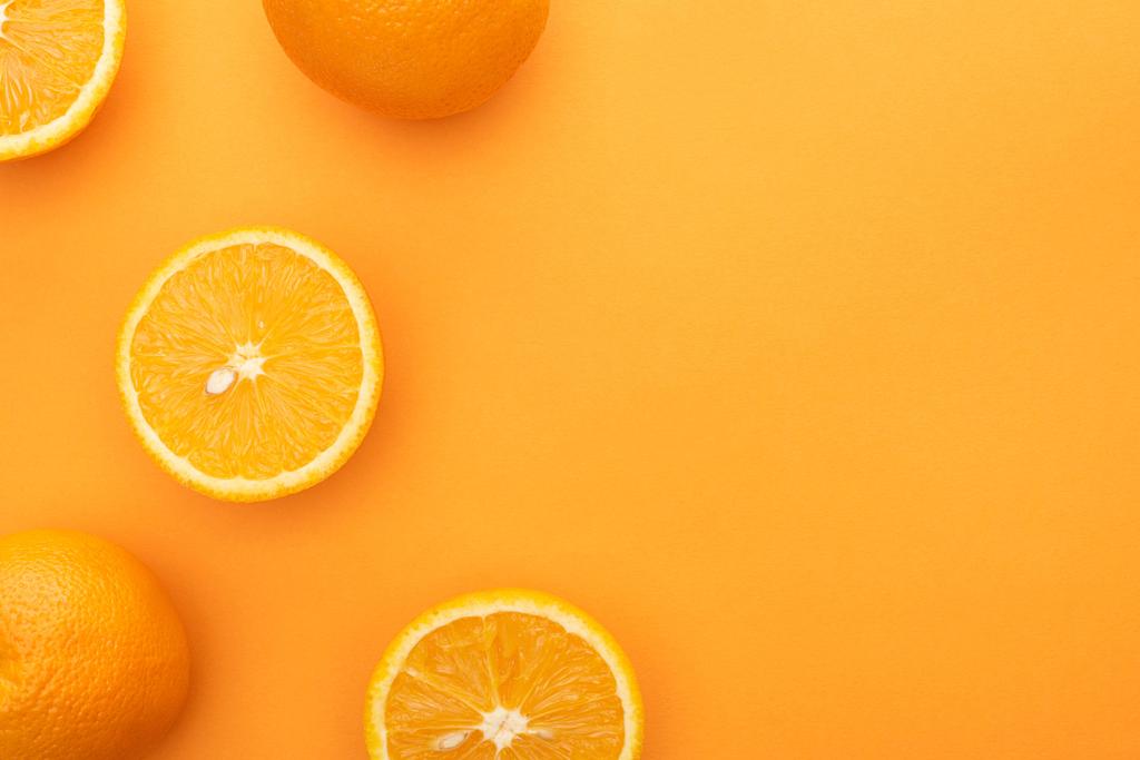widok z góry dojrzałych soczyste całe pomarańcze i plastry na kolorowe tło - Zdjęcie, obraz