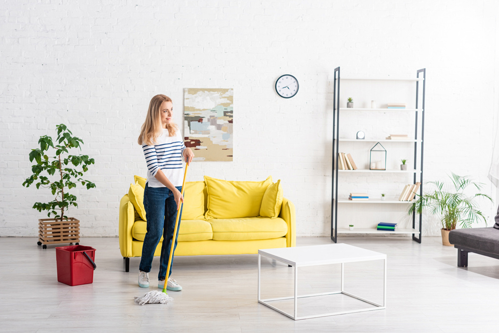 Mulher loira limpando com esfregona na sala de estar
 - Foto, Imagem