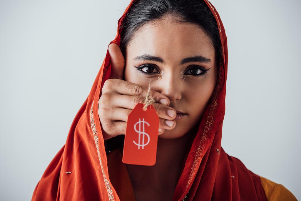 Männliche Hand hält Preisschild mit Dollarzeichen in der Nähe Gesicht der weinenden indischen Frau isoliert auf grau - Foto, Bild