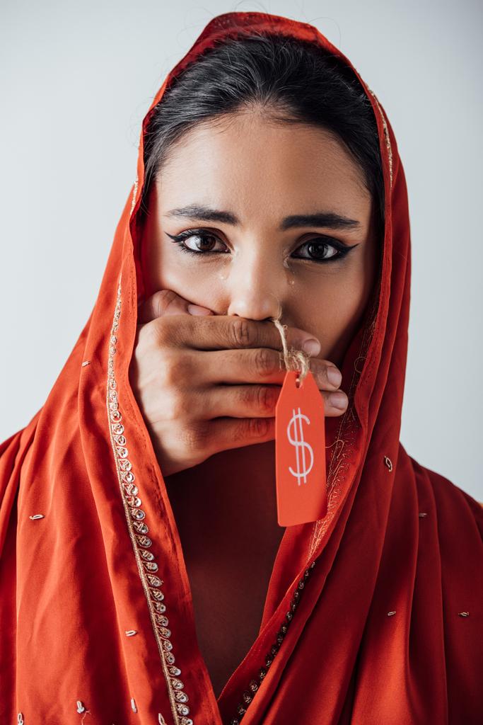 Férfi kéz gazdaság árcédula dollár jel és fedő száj síró indiai nő szári elszigetelt szürke  - Fotó, kép
