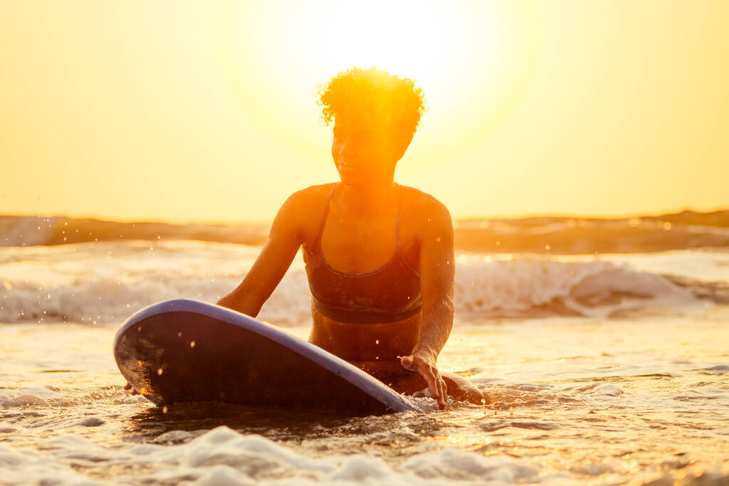 Brasilianische Amerikanerin mit Brett bei Sonnenuntergang entspannen - Foto, Bild
