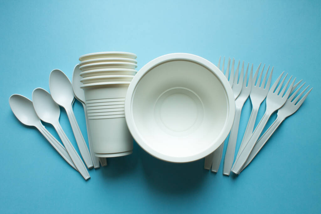 Одноразовий біорозкладний посуд: тарілки, окуляри та ложки з виделками на синьому фоні крупним планом копіюють простір. Тенденція: екологія
. - Фото, зображення