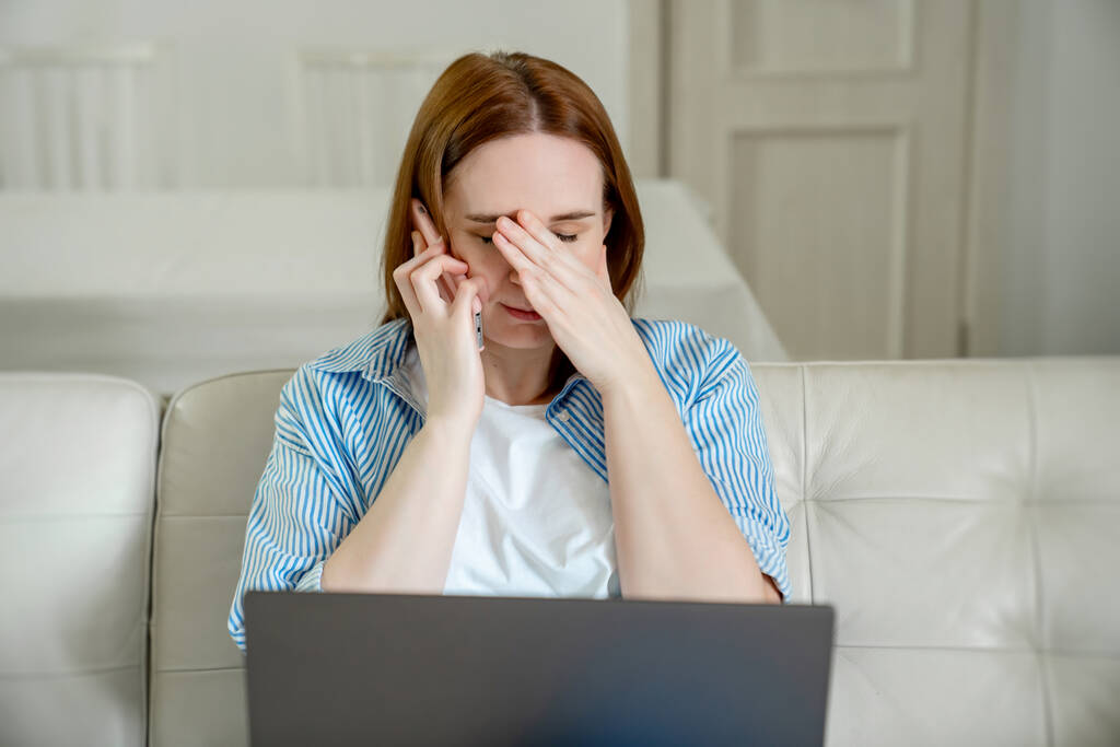 sírni nő kanapén segítségével számítógép beszél telefonon - Fotó, kép