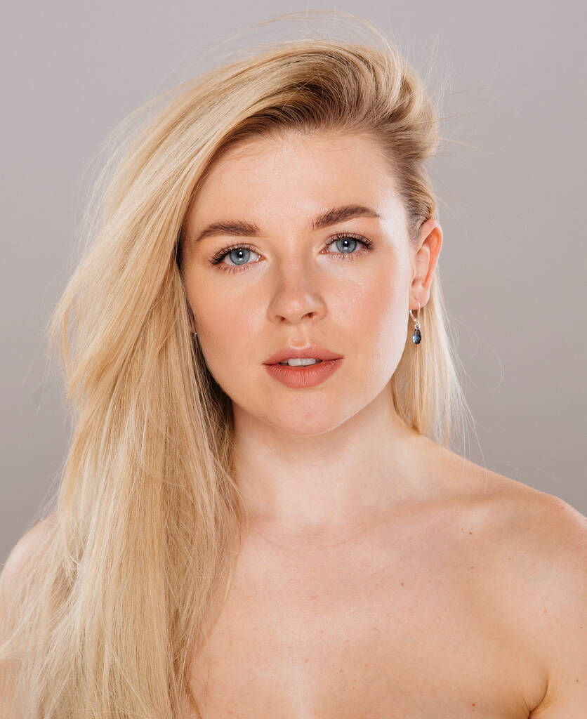 close-up portret van mooie blonde vrouw poseren in studio tegen naakt achtergrond - Foto, afbeelding