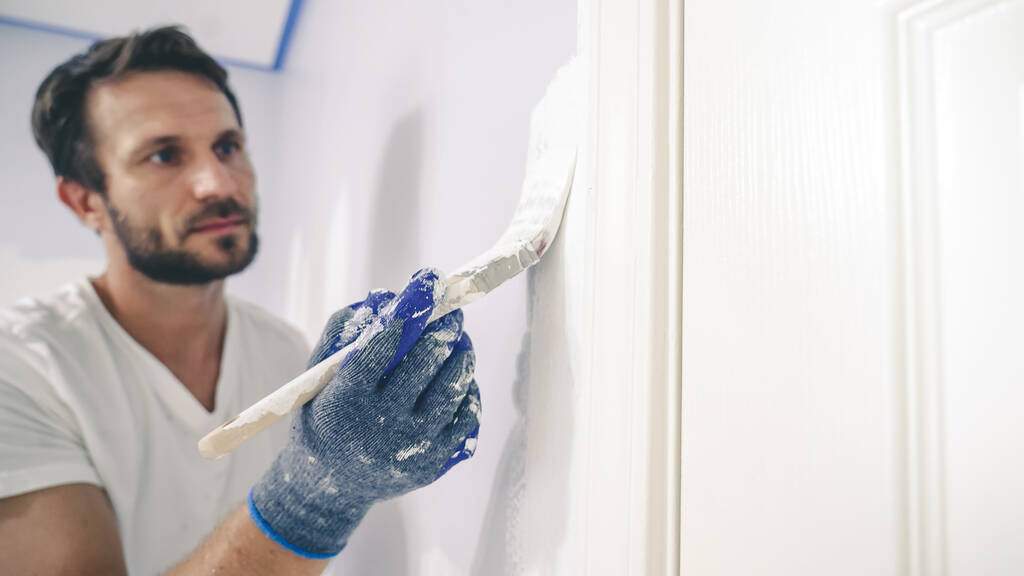 Közelkép a festő kezét kesztyű festés a fal szélén ajtóról keretre.  - Fotó, kép