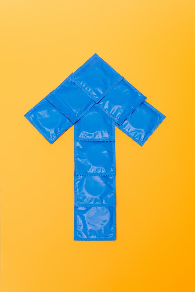 pohled shora na šipku z balíčků s kondomy izolovanými na oranžové  - Fotografie, Obrázek
