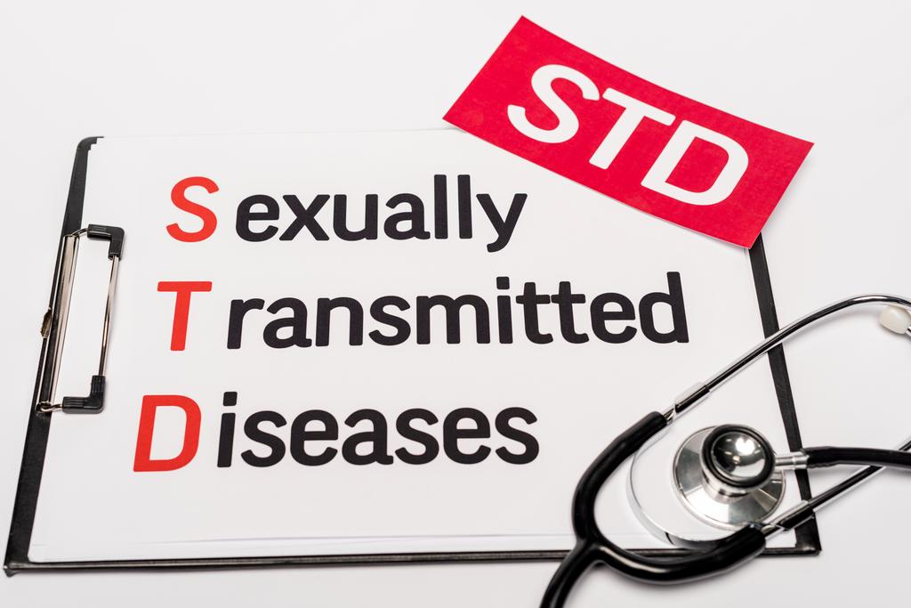 vista superior da área de transferência com doenças sexualmente transmissíveis perto de papel vermelho com letras std e estetoscópio isolado em branco
 - Foto, Imagem