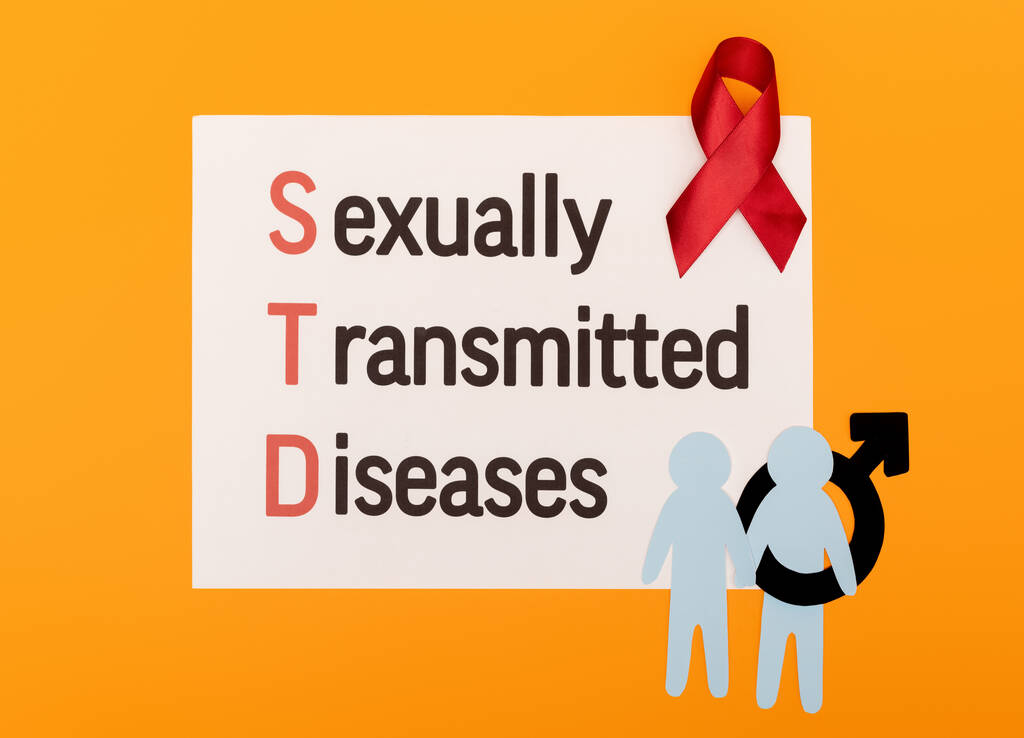 ylhäältä näkymä paperi miesten sukupuoli symboli lähellä punainen nauha ja paperi sukupuolitautien kirjoitus eristetty oranssi
 - Valokuva, kuva
