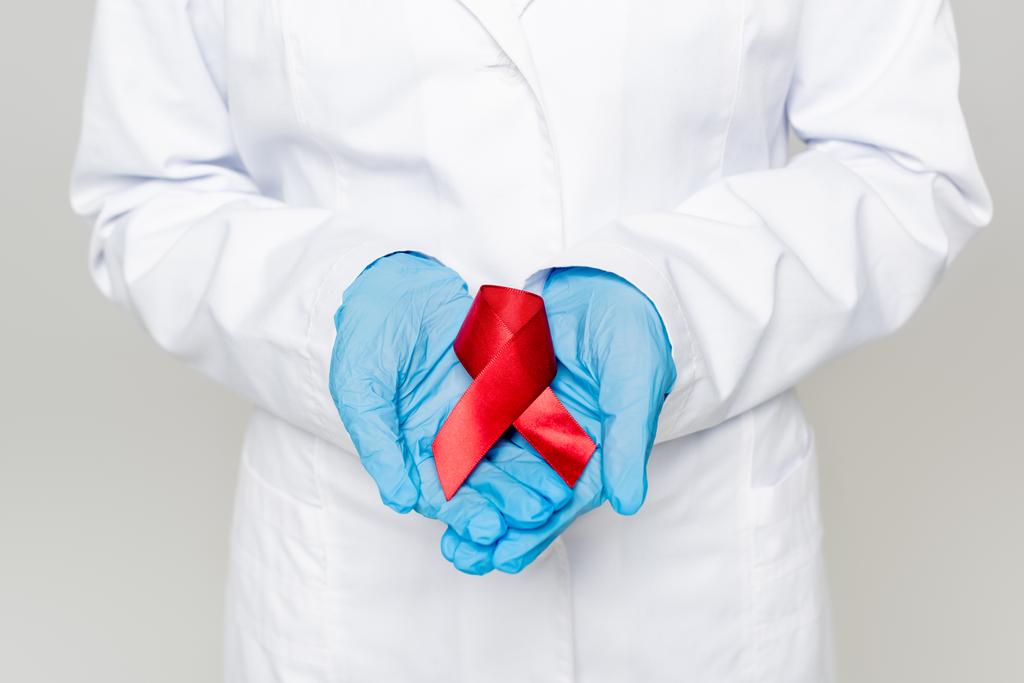 灰色に隔離された赤いリボンを持つ医師のクロップドビュー  - 写真・画像