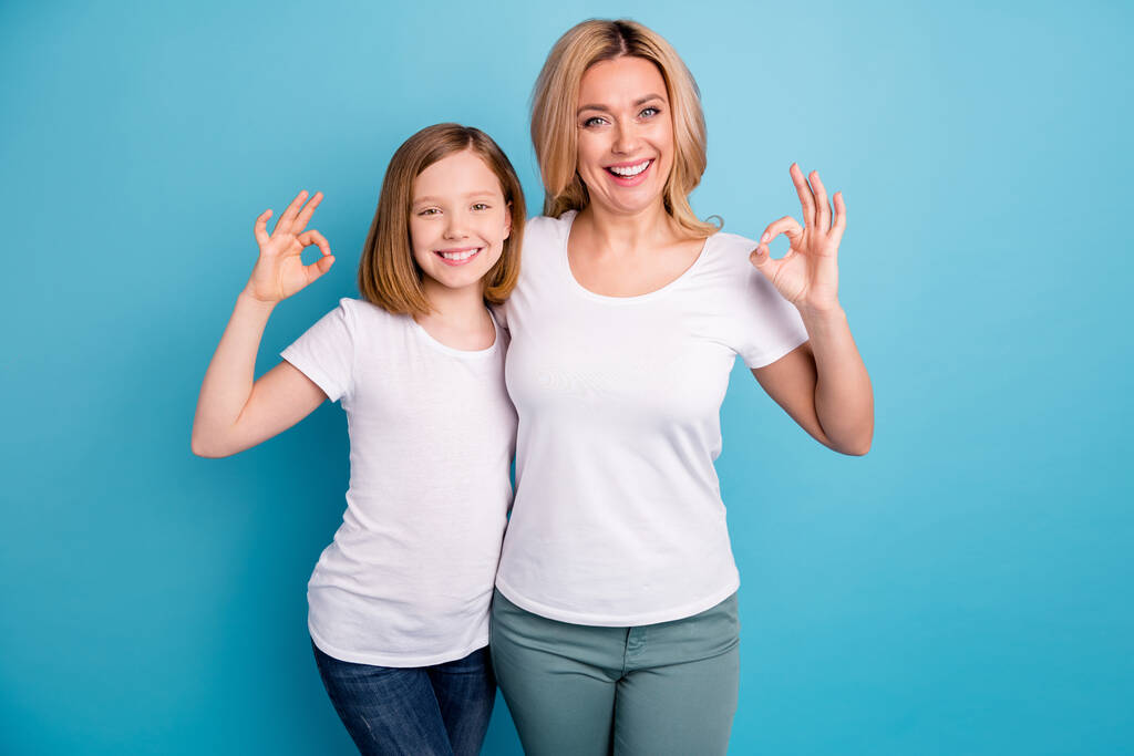 Fénykép két ember fiatal gyönyörű anya hölgy kis lánya jó hangulat mutató okey szimbólumok kifejezett megállapodás viselni alkalmi fehér s-ingek elszigetelt kék színű háttér - Fotó, kép