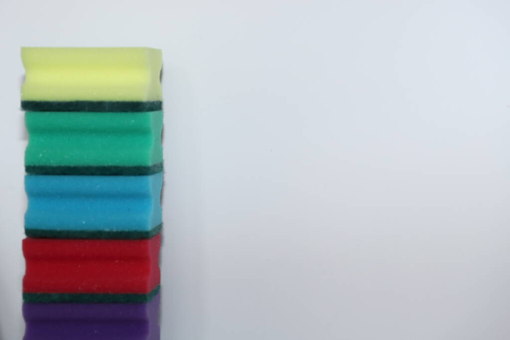 Beyaz arka planda bulaşık yıkamak için yeşil sarı kırmızı mavi sünger köpüğü arka plan olarak kullanılıyor. - Fotoğraf, Görsel