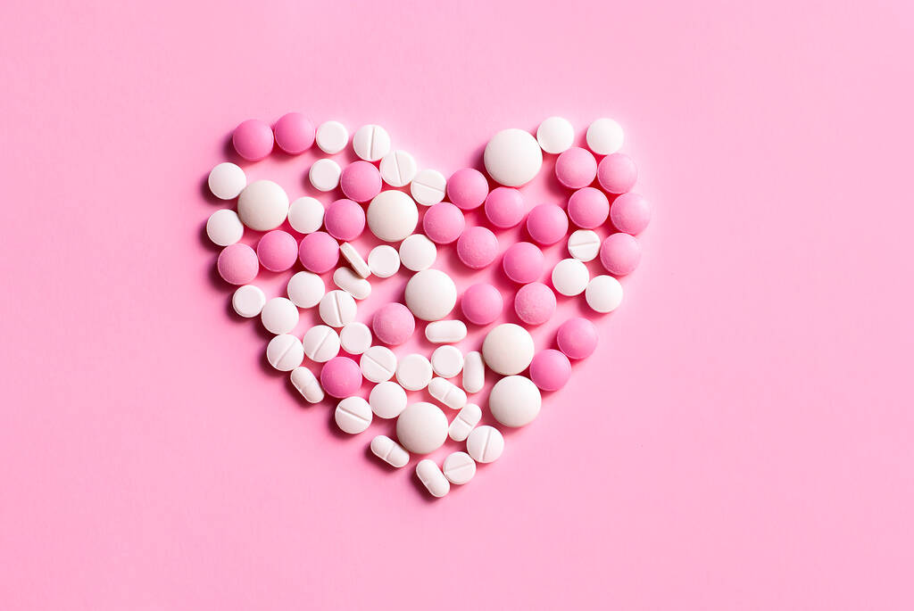 Beautiful heart symbol made from pills medicine health care concept. Flat lay top view picture on the pink background - Photo, Image
