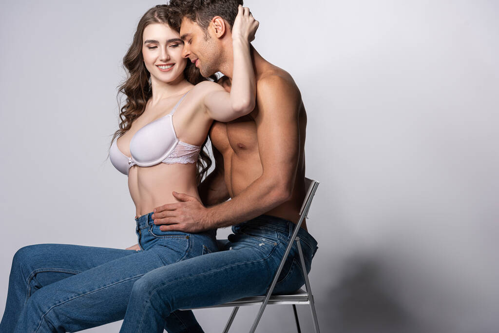 onnellinen nainen rintaliivit koskettaa paidaton mies farkut istuu harmaa
  - Valokuva, kuva
