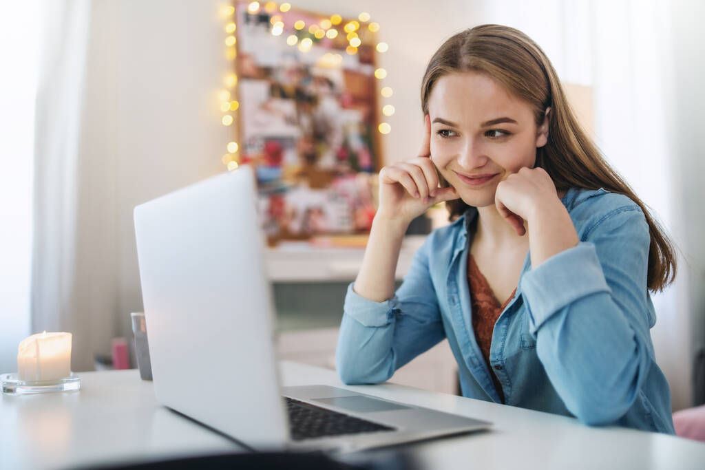 Όμορφη ευτυχισμένη νεαρή κοπέλα με φορητό υπολογιστή κάθεται και χαμογελώντας, online dating έννοια. - Φωτογραφία, εικόνα