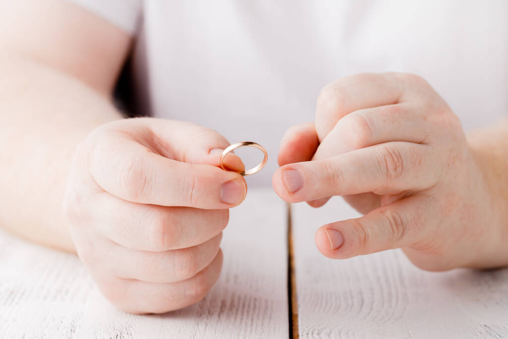 El hombre quita un anillo de bodas de oro de su dedo. Concepto de disputa familiar, divorcio o traición
 - Foto, imagen