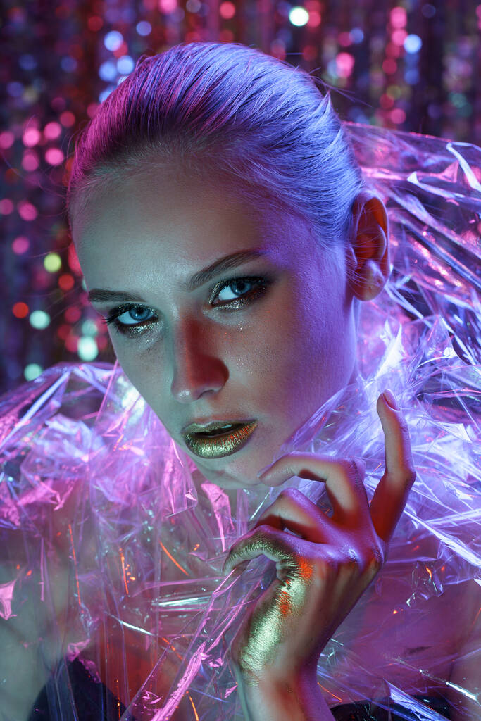 Menina modelo de alta moda em luzes de néon brilhantes coloridas posando em estúdio através de filme transparente. Retrato de bela mulher sexy em UV. Design de arte colorido compõem. Sobre fundo vívido colorido - Foto, Imagem