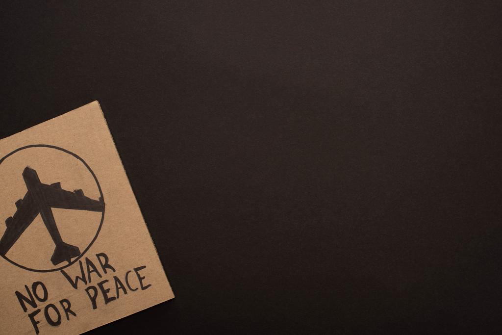 Ansicht von Pappplakat ohne Krieg für den Frieden und Flugzeug auf schwarzem Hintergrund - Foto, Bild