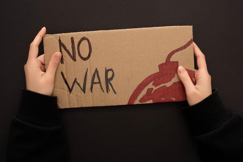 vue recadrée de la femme tenant une plaque en carton sans lettrage de guerre et la bombe sur fond noir
 - Photo, image