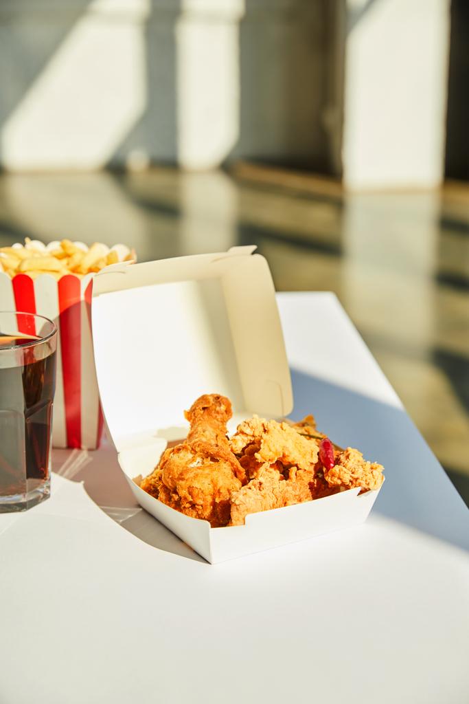 tasty deep fried chicken, french fries and soda in glass on white table in sunlight - Photo, Image