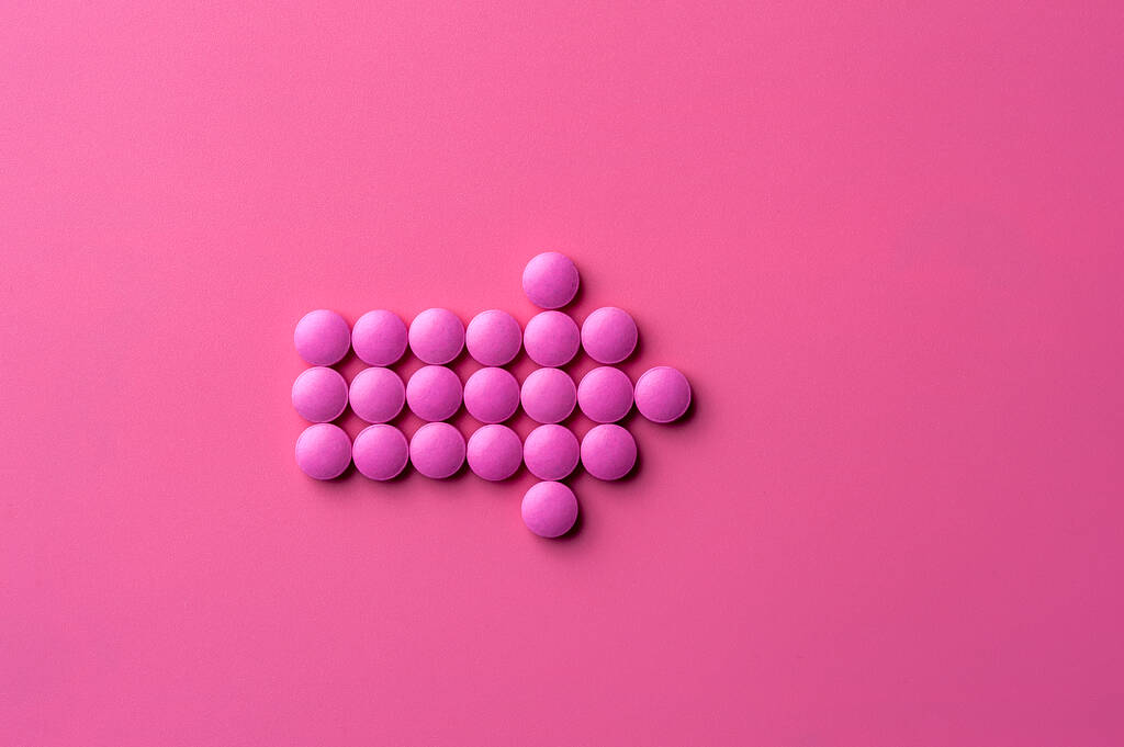 Close-up van roze pillen liggen op een roze oppervlak - Foto, afbeelding