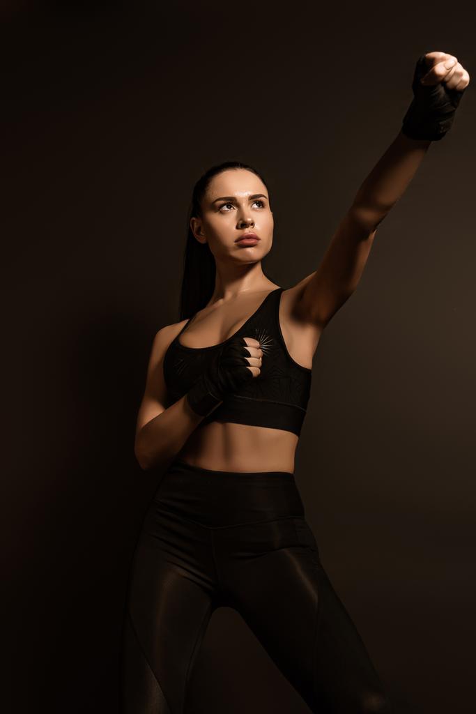 Krásná sportovkyně ve sportovních rukavicích s nataženou rukou izolované na černé - Fotografie, Obrázek