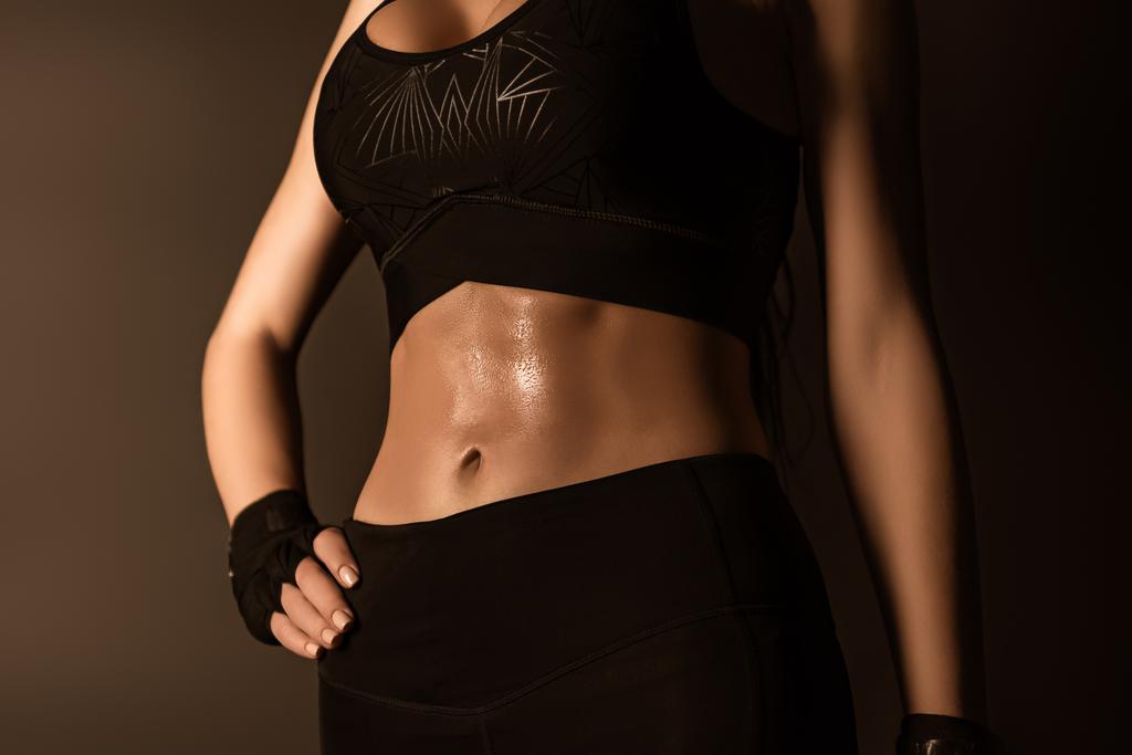 Oříznutý pohled na sexy sportovkyně s rukou na boku izolované na černé - Fotografie, Obrázek