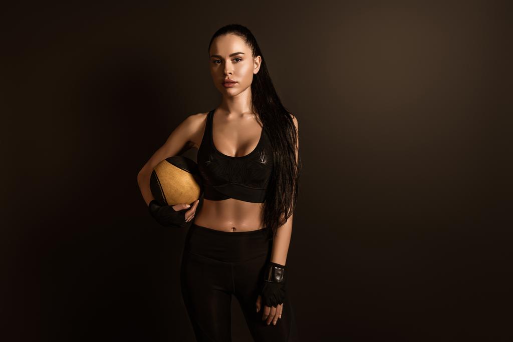 Morena deportista con bola mirando a la cámara aislada en negro
 - Foto, Imagen