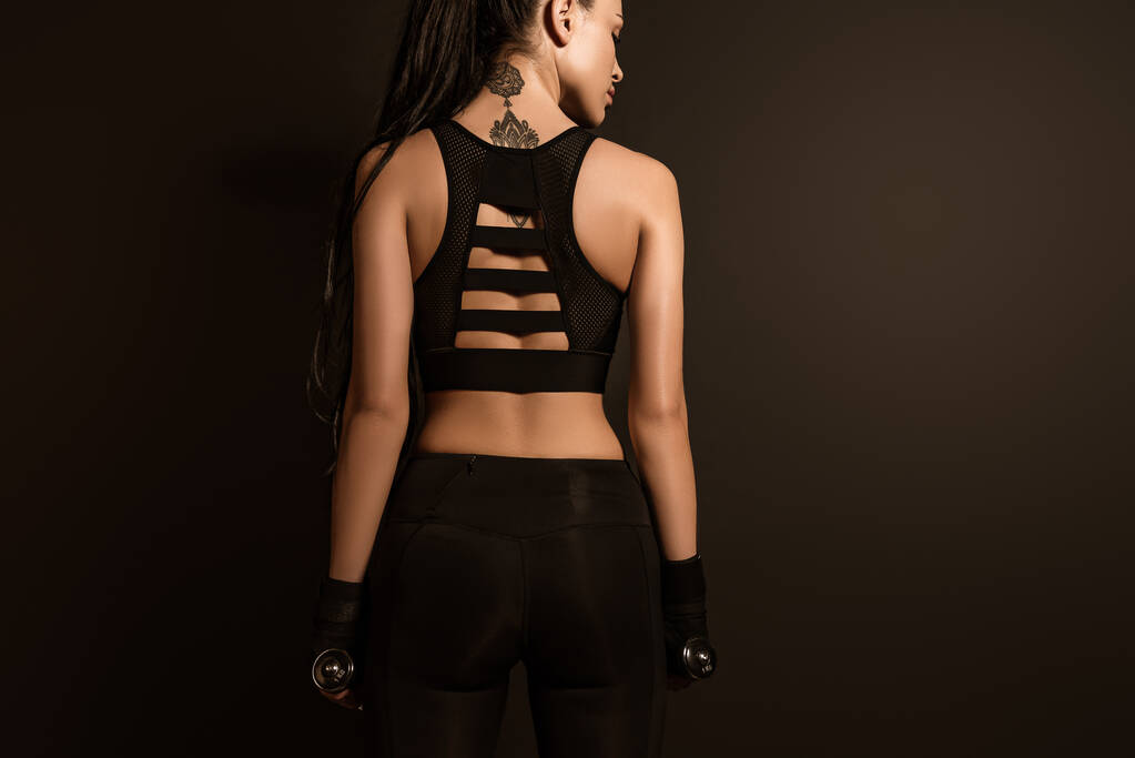 Вид збоку спортсменки з гантелями ізольовані на чорному
 - Фото, зображення