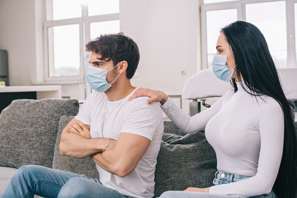 ofendido homem e mulher em máscaras médicas em casa durante o auto-isolamento
 - Foto, Imagem